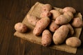 A pile of potatoes on burlap on a dark wood background