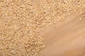 Pile of raw barley, natural grain on wooden background, cereal backdrop, brown yellow beige colour, textured backgrounds
