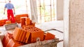 Pile of red blocks in wheelbarrow, worker builds wall with bricks and mortar, building site Royalty Free Stock Photo