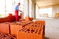 Pile of red blocks, worker builds wall with bricks and mortar, building site Royalty Free Stock Photo
