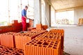 Pile of red blocks, worker builds wall with bricks and mortar, building site Royalty Free Stock Photo