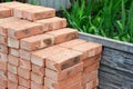 A pile of red bricks are neatly piled together on the construction site to build a brick wall of the house