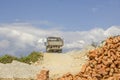 Pile of red bricks and a truck on a mountain road against the backdrop of snowy mountains and a blue sky Royalty Free Stock Photo