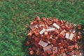 A pile of red broken bricks on a green lawn Royalty Free Stock Photo