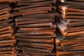 A pile of red clay roofing tiles stacked on top of each other, looking at the long edge of the tiles