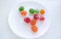 A pile of red, green and yellow jelly cubes on a white plate on a white background. Royalty Free Stock Photo