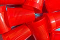 Pile of red plastic drinking cup on blue background. Environmental protection plastic-free alternatives nature friendly living