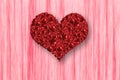 Pile of red rose in heart shape on pink background.