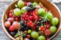 Pile of ripe berries in a clay pot, blackcurrant, redcurrant, gooseberry, blackberry. Sweet and sour vegeterian diet