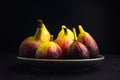 Pile of ripe figs fruit are on a plate with black background. Royalty Free Stock Photo