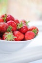 Pile of ripe, red strawberries in a white bowl.