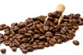 Pile of roasted coffee beans with wooden scoop on white background, selective focus Royalty Free Stock Photo