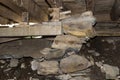 A pile of rocks, blocks of wood, and a wooden beam hold up a floor in an unfinished basement.