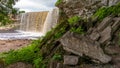 Pile of rocks in the foreground and a waterfall on the background Royalty Free Stock Photo