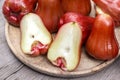 A pile of rose apples with a slice in a wooden tray on the table Royalty Free Stock Photo