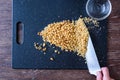 Pile of rough chopped and fine chopped walnuts on a black cutting board, womanÃ¢â¬â¢s hand on chef knife, glass bowl. Royalty Free Stock Photo
