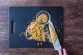 Pile of rough chopped and fine chopped walnuts on a black cutting board, womanÃ¢â¬â¢s hand on chef knife, glass bowl.