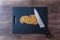 Pile of rough chopped walnuts on a black cutting board, chef knife, on dark wood table Royalty Free Stock Photo