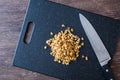 Pile of rough chopped walnuts on a black cutting board, chef knife, on dark wood table Royalty Free Stock Photo