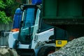 A pile of rubble and soil in the foreground. in the background a mini bulldozer loader Royalty Free Stock Photo