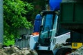 A pile of rubble and soil in the foreground. in the background a mini bulldozer loader Royalty Free Stock Photo