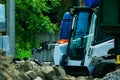 A pile of rubble and soil in the foreground. in the background a mini bulldozer loader