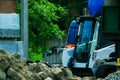 A pile of rubble and soil in the foreground. in the background a mini bulldozer loader Royalty Free Stock Photo