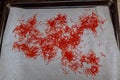 Pile of saffron stamens on white parchment.