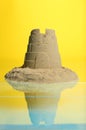 Pile of sand with tower on mirror surface against yellow. Beautiful castle Royalty Free Stock Photo