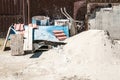 Pile of sand with trolley and other architectural material and tools in front of the residential building constriction site on the Royalty Free Stock Photo