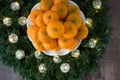 Pile of satsuma oranges on a white plate, in a wreath with LED Christmas lights on a wood background Royalty Free Stock Photo