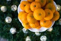 Pile of satsuma oranges on a white plate, in a wreath with LED Christmas lights on a wood background Royalty Free Stock Photo