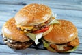 Pile of sesame buns of fried breaded chicken fillet patties, crisp lettuce, melting cheese, onions and sauce, juicy thick double Royalty Free Stock Photo