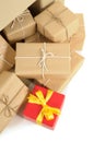 Pile of several brown paper parcels and single unique small red christmas gift, white background