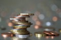 Pile of shiny coins different sizes and colors stacked unevenly on each other on colorful blurred blue abstract background. Money Royalty Free Stock Photo