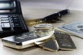 A pile of silver bars and coins, dollar bills, gold credit card, pen and a calculator