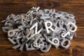 Pile of silver metal alphabet characters cutted by waterjet machine in wooden background