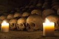 A pile of skulls laid on the ground at candle light in an ossuary