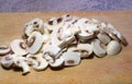 Pile of sliced raw button mushrooms on a board.