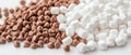 A pile of small brown chocolate chips next to a pile of fluffy white marshmallows on a plain background. Royalty Free Stock Photo