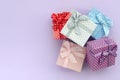 Pile of a small colored gift boxes with ribbons lies on a violet background. Minimalism flat lay top view Royalty Free Stock Photo