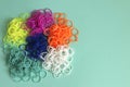 Pile of small round colorful rubber bands for making rainbow loom bracelets isolated on mint background