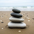 A pile of smooth stones is balanced on a sandy beach. The stack has four stones, ranging from dark Royalty Free Stock Photo