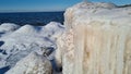 Pile of snowy rocks by the sea on a sunny winter day with a blue sky