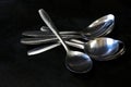 A pile of spoons against a black background on a kitchen table Royalty Free Stock Photo