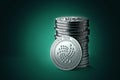 Pile or stack of silver IOTA coins on gently lit green blue background.