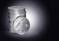 Pile or stack of silver Litecoin coins on gently lit dark blue background