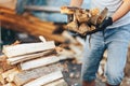 A pile of stacked firewood, prepared for heating the house. Gathering fire wood for winter or bonfire. Man holds fire wood in Royalty Free Stock Photo