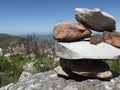 A pile of stacked rocks overlooking a view from a mountain top,  indigenous vegetation blurred in the background Royalty Free Stock Photo