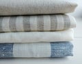 Pile of striped white grey blue linen cotton fabrics on white background.